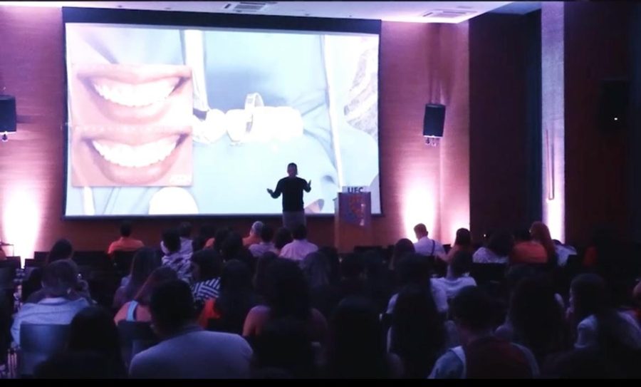 Plateia acompanha comparação de antes e depois de laminados cerâmicos em telão durante palestra
