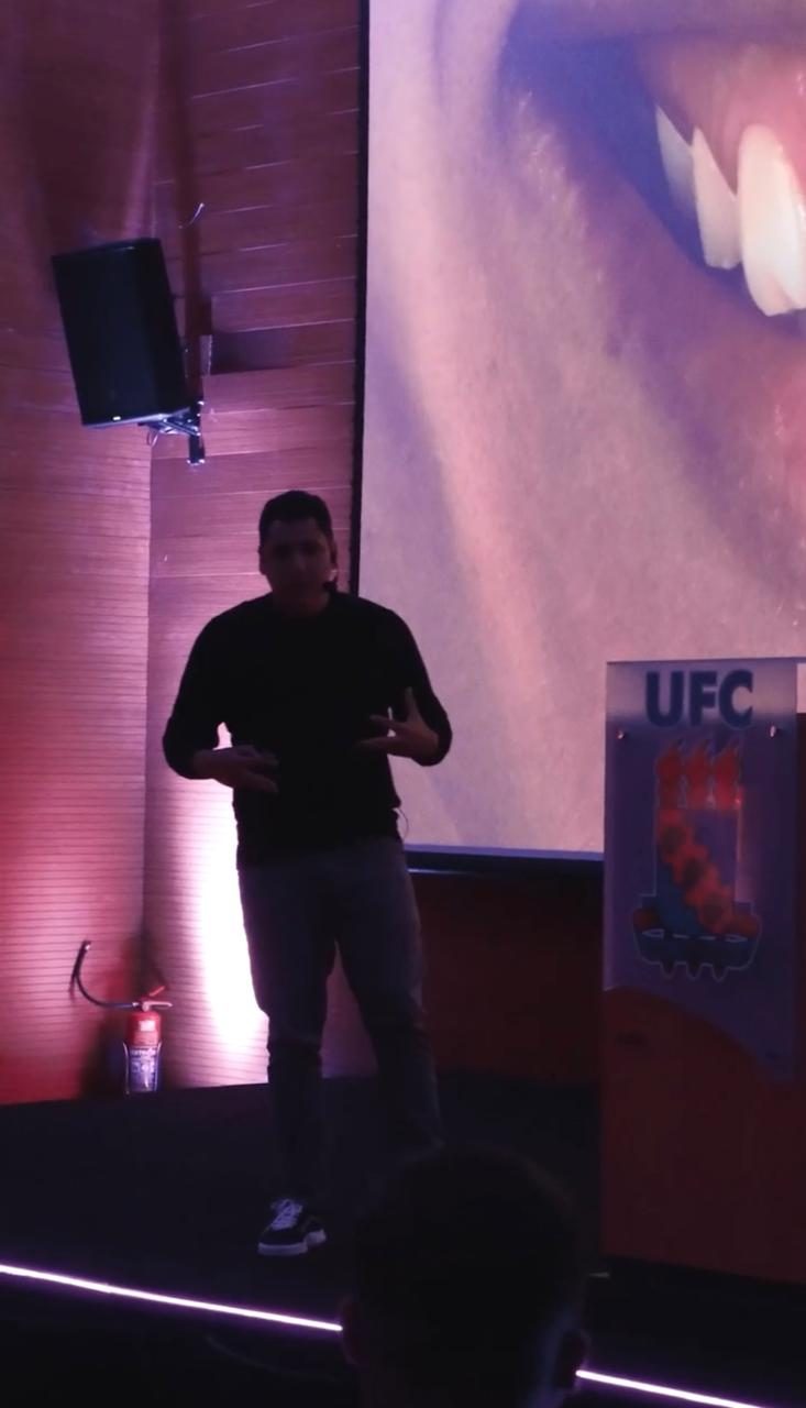 Dr. Augusto Câmara explicando técnica de laminados cerâmicos com imagem clínica ao fundo